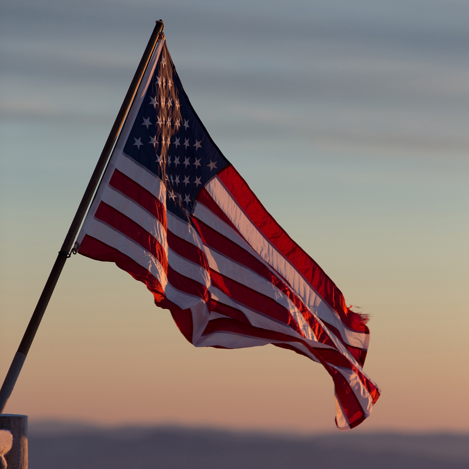 American flag against a muted sunrise