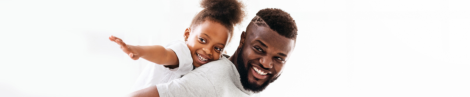 African American father carries smiling daughter on his back