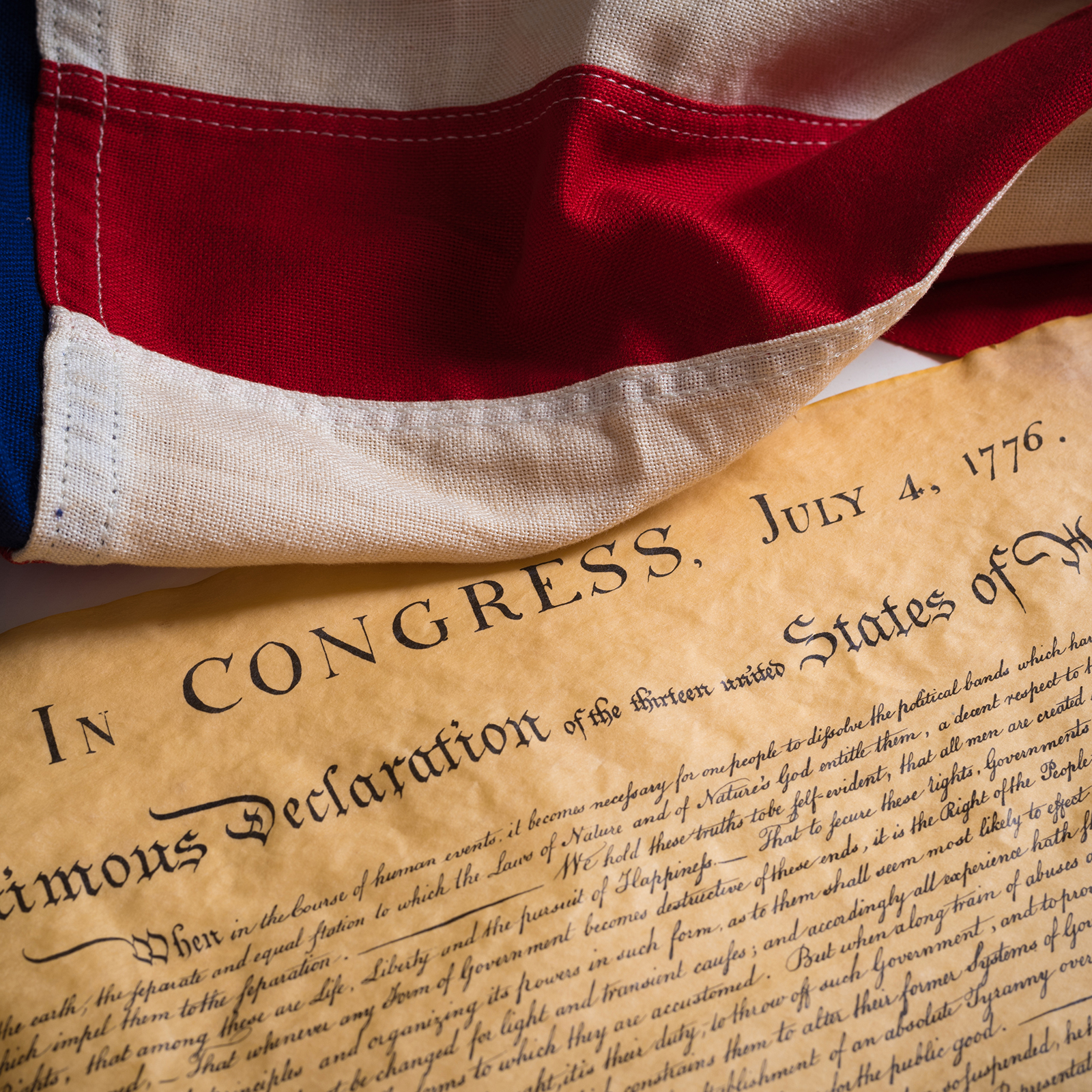 the top portion of the handwritten Declaration of Independence and a portion of the American flag