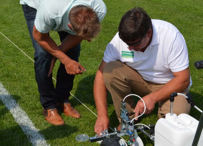 a Turfix member of staff explaining how a line marking machine works to a customer