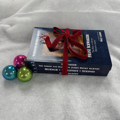 A photo of the four books in the series stacked with their spines showing. They are wrapped in red ribbon and laying on a white background with three small ornaments leaning against them on the left.