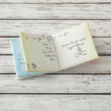 Yellow cloth open book with black quotes on it - laying on white wooden surface