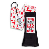 A red and white Christmas themed fabric kitchen boa with black towel ends and a white fabric patch that says "Holiday Baking Elves at Work" shown with a product information tag.
