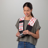 A standing woman wearing a red and white Christmas themed fabric kitchen boa while drying a glass with the black towel ends. One has a white fabric patch that says "Holiday Baking Elves at Work".