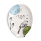white ceramic spoon rest with outline of bird and flowers drawn on and the word 'nibbles'