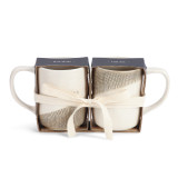 two tan and white ceramic patterned mugs wrapped in a gift set with a white ribbon