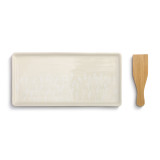 A beige appetizer tray with a white floral print. Placed beside a wooden spatula.