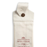 A detailed view of a button loop cream tea towel and cream fabric overlay that says "Will Cook for Wine". The button loop and top of the towel is cream with a brown button shown unbuttoned and offset.