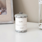 A blue, white, and silver luxurious keepsake jar with two sections; tooth and curl, displayed on a white table.