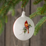 Cardinal with lifelike detailing on a round ceramic ornament hanging from a christmas tree