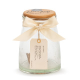 A round glass container with a round wood lid that says "Dear Baby". The jar has a cream ribbon and paper tag with a sentimental message to baby.