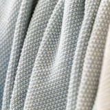 Close up detailed view of a blue and cream ombre knit blanket.