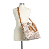 A cream tote bag with brown spots and a leather shoulder strap and handles displayed on a mannequin.