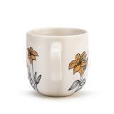 The handle of a cream coffee mug with several simple black and orange flowers stemming from the base.