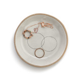 A round ceramic treasure keeper dish with a tan textured rim and intersecting rings. The dish has a necklace and ring inside.