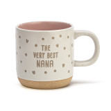 Front view of a cream handled ceramic mug that says "The Very Best Nana" in brown along with dots and hearts. The interior of the mug is pink.