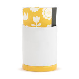 The back view of a white ceramic planter with a yellow base. There is a paper journal inside.