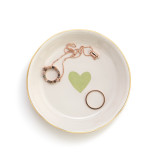 A small white ceramic treasure keeper dish holding a ring and necklace. The dish has a light green heart and gold rim.