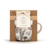 A front facing view of a cream coffee mug with several simple black and light pink roses stemming from the base. Placed in a cardboard packaging.