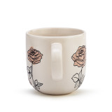The handle of a cream coffee mug with several simple black and light pink roses stemming from the base.