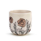 A side view of a cream coffee mug with several simple black and light pink roses stemming from the base.