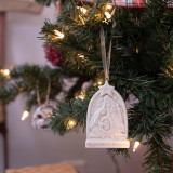 One of a set of three nativity scene engraved triptych ornaments, each with a different scene and story in gold lettering, displayed on a Christmas tree.