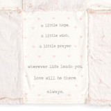 Detail view of the bottom center panel on a pink and cream blanket with a dark pink pocket in the middle. There are inspirational sayings on the top and bottom center sections.