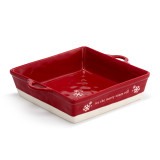 A square red ceramic dish with side handles that says "let the merry times roll" with a white base, displayed angled to the right.