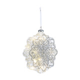 A glass snowflake shaped ornament with silver highlights and is lit from within, displayed angled to the right.