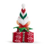 Closed back view of a slap bracelet in a red and green knit pattern with the head of a light skinned elf in the middle.