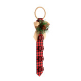 A red and black plaid fabric door hanger with four large red bells and a gold bow and pine decoration at the top, displayed angled to the right.