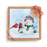 A square ceramic trivet in a cork base. The tile has a watercolor image of a snowman and two cardinals, displayed with a product tag attached.