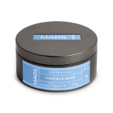 A dark metal round travel tin candle with the lid on and a Clear Blue Water scent.