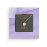 Top down view of a small square purple book with inspirational content about friendship. There is a gold chain necklace inside with a round charm.