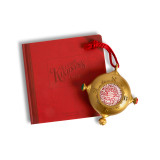 Top down view of a gold ornament that looks a bit like a compass on a red hanger. There is a QR code in the center to scan for videos, displayed next to a red bound journal that says "Santa's Kindness Journal". Top down view of a gold ornament that looks a bit like a compass on a red hanger. There is a QR code in the center to scan for videos, displayed next to a red bound journal that says "Santa's Kindness Journal".