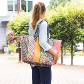 Side view of model using should straps to hold bag on her right side.