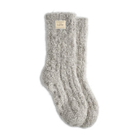 A pair of gray fuzzy socks with a small cream Giving Collection fabric tag attached.