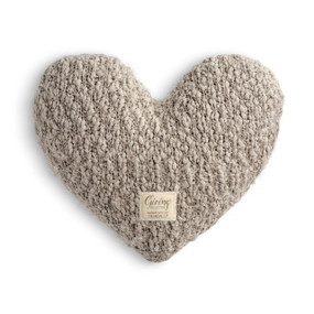 A taupe colored heart shaped Giving Collection pillow with a small cream Giving Collection fabric tag attached.