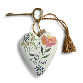 White heart with green leaves and stems and pink and yellow flower has black lettering. Bronze key and tassel are attached to top of heart