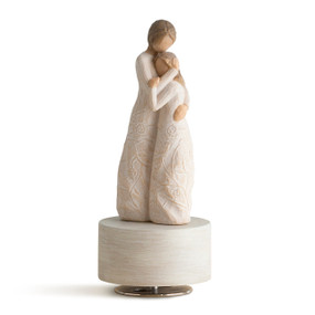Two standing female figures, one younger, wearing cream dresses carved with vines and leaves with arms wrapped around each other, on cream wood base