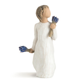 Front view of standing figure in cream dress holding bunches of lavender in each hand