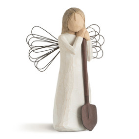 Front view of female figure in cream dress with wire wings, holding brown metal shovel in her hands
