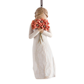 Figure in cream dress holding large bouquet of red-orange poppies up to face, ornament hook attached to head