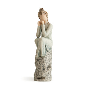 Front view of figure in light blue dress sitting on rock carved with symbols and words