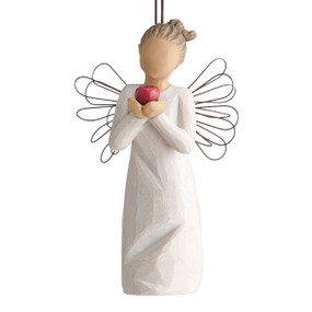 Front view of figure in cream dress with wire wings holding large red apple in hands, ornament hook on head