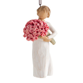 Front view of female figure with short brown hair holding large bouquet of pink roses, ornament loop affixed to top of head