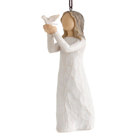 Front view of female figure in cream dress holding out a white dove, ornament hook and loop affixed to figure's head