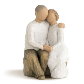 Male and female couple figures seated next to each other on bench, holding hands