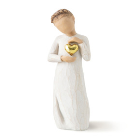 Front view of standing female figure in cream dress with braid around head, holding gold-leaf heart with both hands to her chest