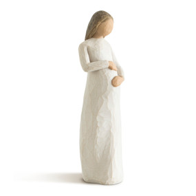 Front view of female in cream dress, with medium-length brown hair, holding pregnant belly with hands